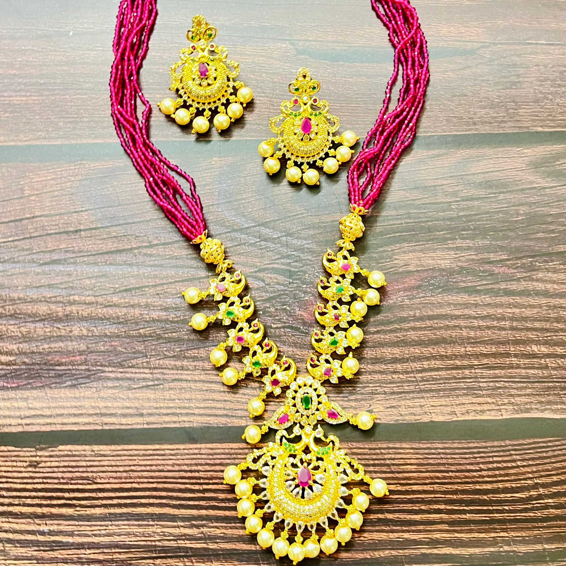 traditional jewelry, temple jewelry, bridal necklace, pearl necklace, ethnic wear, gold plated jewelry, South Indian jewelry, handcrafted jewelry, festive wear, statement necklace, antique finish, Indian bride, designer jewelry, heavy necklace set, wedding collection, navratna stones, ruby emerald combo, temple earrings, kundan work, goddess jewelry, mangalsutra look, cultural heritage, pink thread necklace, handmade jewelry, fashion accessories
