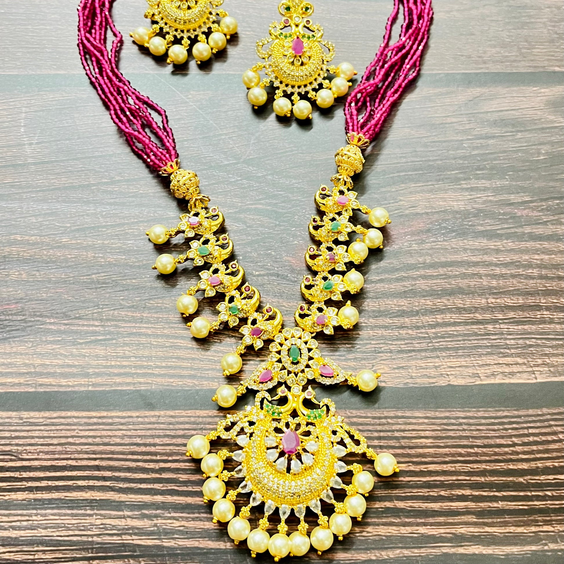 traditional jewelry, temple jewelry, bridal necklace, pearl necklace, ethnic wear, gold plated jewelry, South Indian jewelry, handcrafted jewelry, festive wear, statement necklace, antique finish, Indian bride, designer jewelry, heavy necklace set, wedding collection, navratna stones, ruby emerald combo, temple earrings, kundan work, goddess jewelry, mangalsutra look, cultural heritage, pink thread necklace, handmade jewelry, fashion accessories