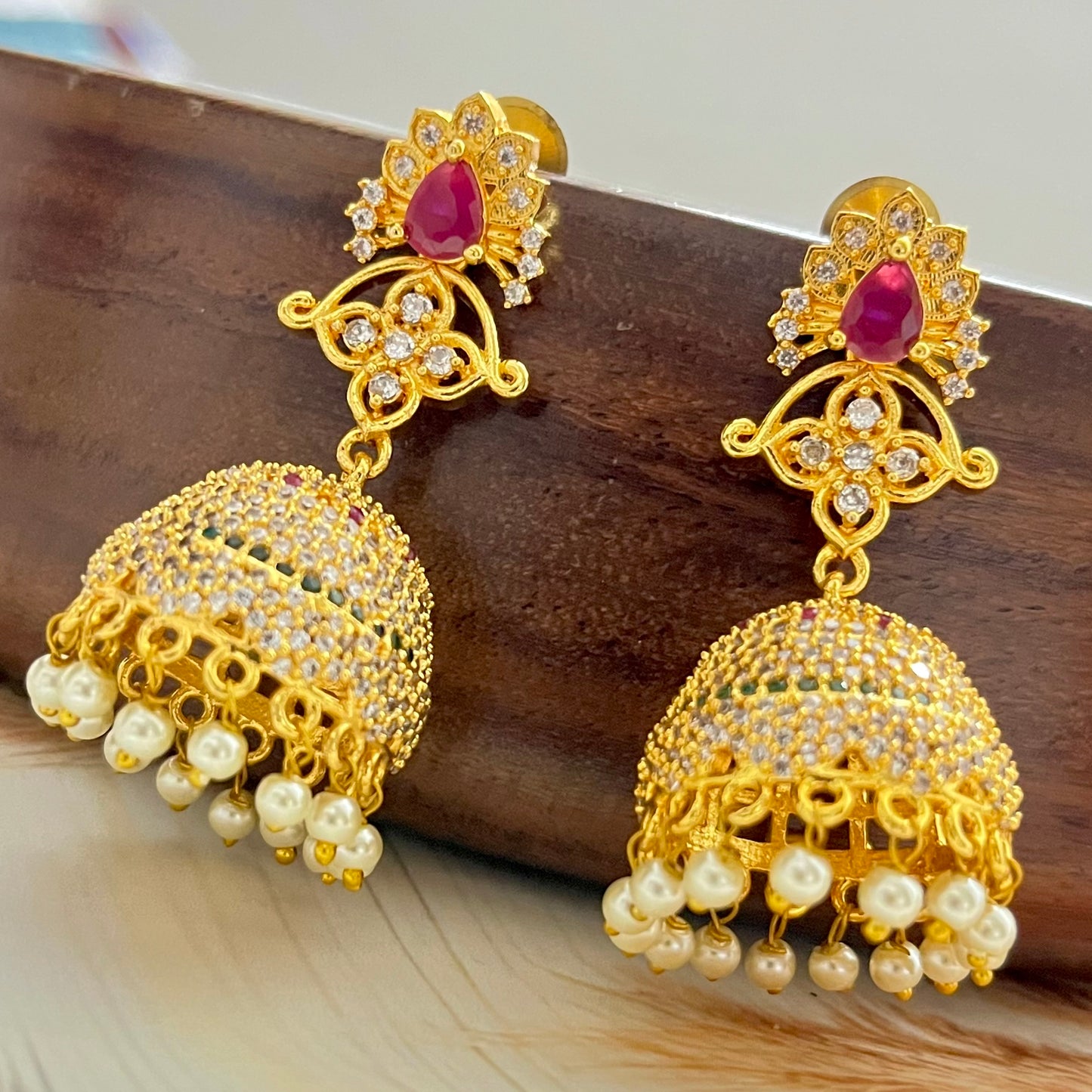 ruby stone jhumka earrings, gold jhumka earrings, traditional jhumka earrings, bridal jhumka earrings, ethnic gold earrings, Indian jhumka earrings, gold plated jhumkas, wedding jewelry for women, temple jewelry earrings, red stone jhumka, pearl drop jhumka, antique gold earrings, festive wear earrings, South Indian jhumka, handcrafted jhumka earrings, CZ stone jhumka, ruby earrings for lehenga, gold earrings for saree, designer jhumka earrings, statement traditional earrings