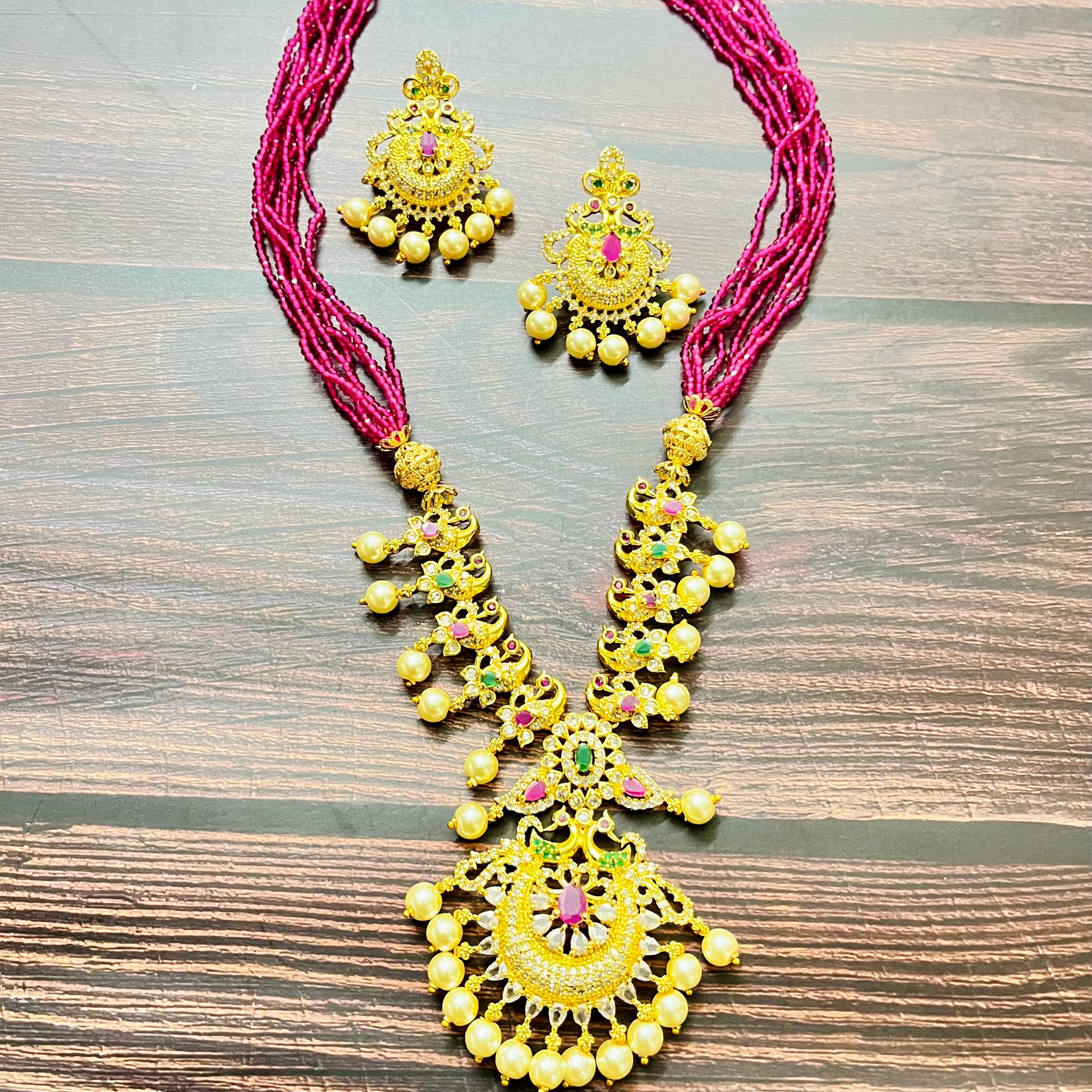 traditional jewelry, temple jewelry, bridal necklace, pearl necklace, ethnic wear, gold plated jewelry, South Indian jewelry, handcrafted jewelry, festive wear, statement necklace, antique finish, Indian bride, designer jewelry, heavy necklace set, wedding collection, navratna stones, ruby emerald combo, temple earrings, kundan work, goddess jewelry, mangalsutra look, cultural heritage, pink thread necklace, handmade jewelry, fashion accessories