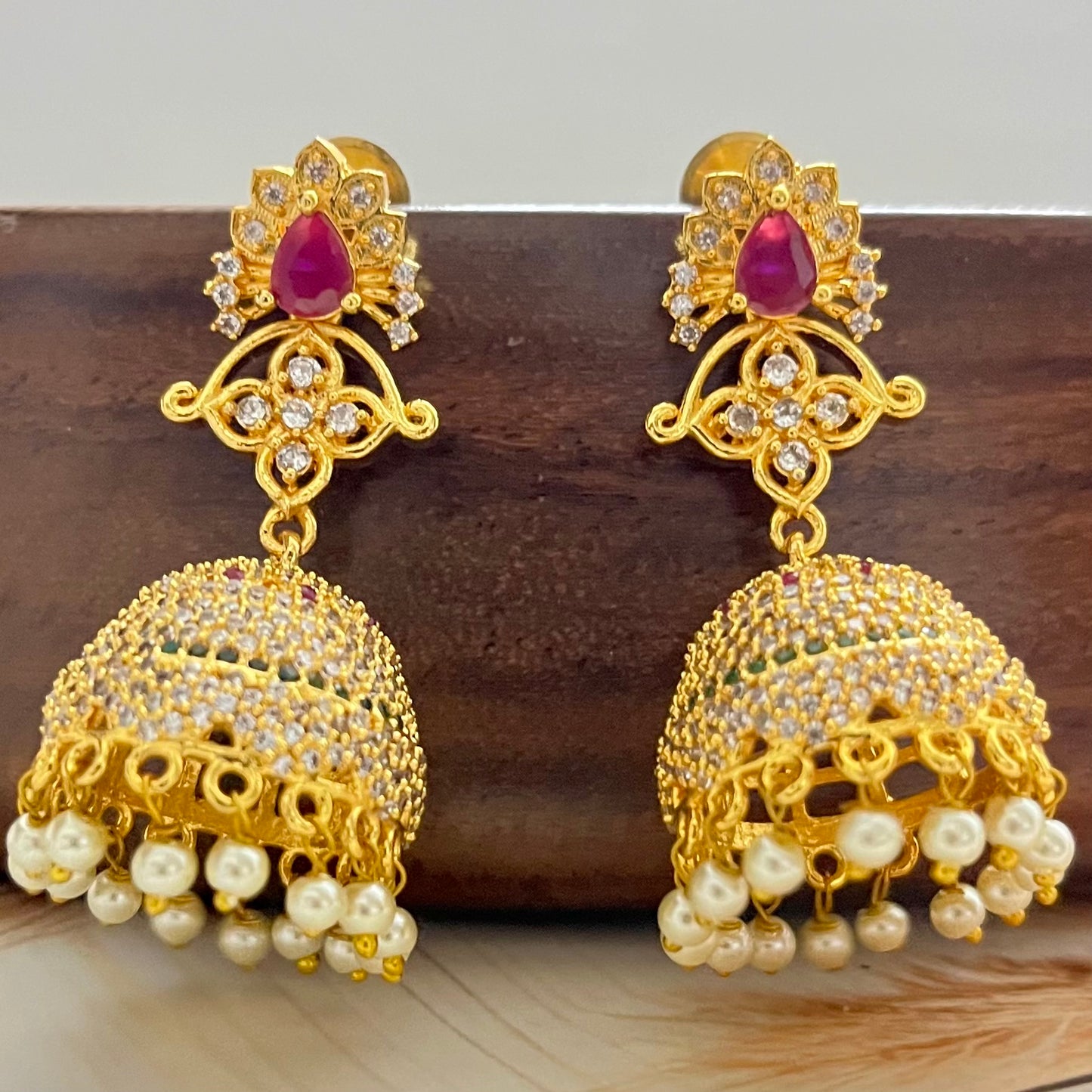 ruby stone jhumka earrings, gold jhumka earrings, traditional jhumka earrings, bridal jhumka earrings, ethnic gold earrings, Indian jhumka earrings, gold plated jhumkas, wedding jewelry for women, temple jewelry earrings, red stone jhumka, pearl drop jhumka, antique gold earrings, festive wear earrings, South Indian jhumka, handcrafted jhumka earrings, CZ stone jhumka, ruby earrings for lehenga, gold earrings for saree, designer jhumka earrings, statement traditional earrings