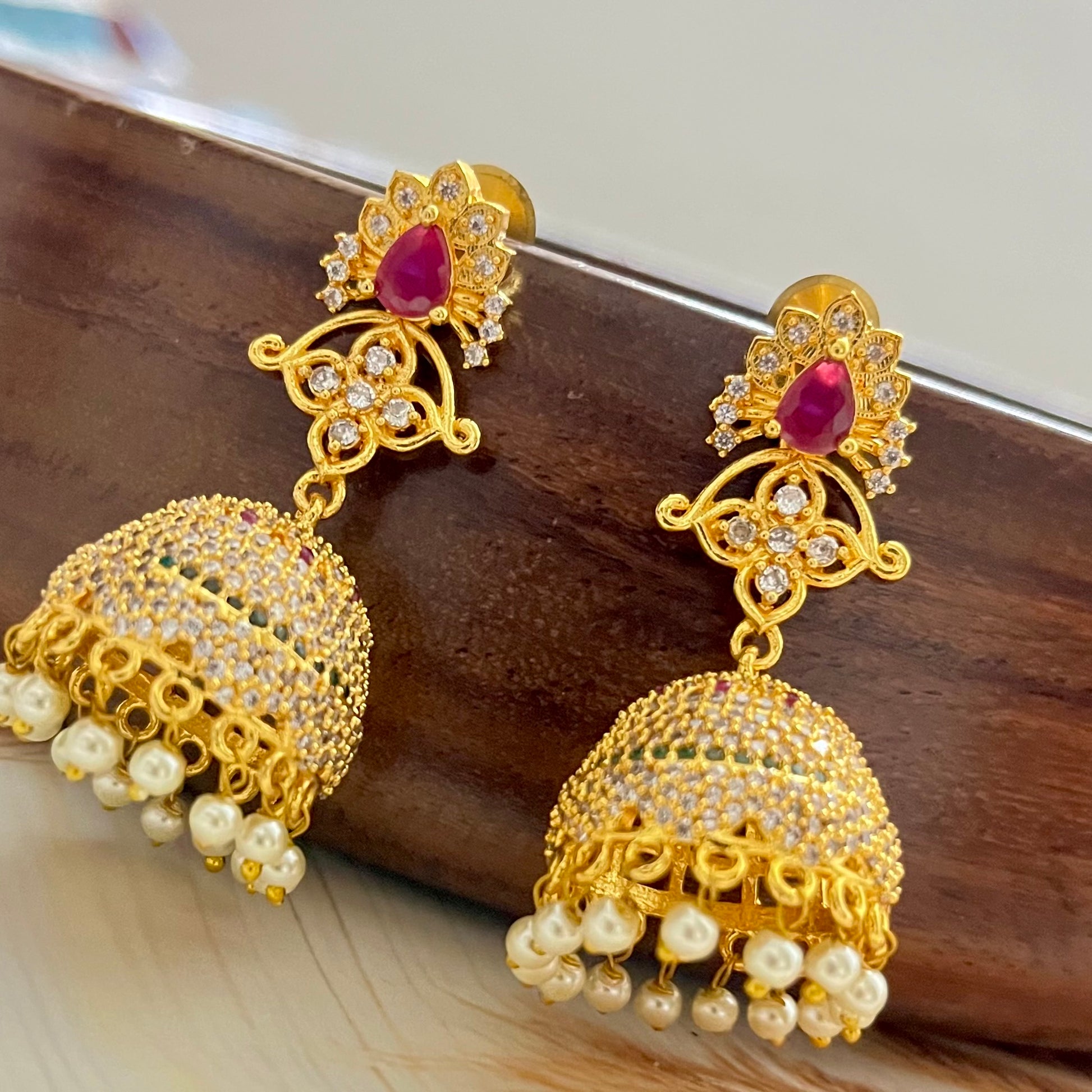 ruby stone jhumka earrings, gold jhumka earrings, traditional jhumka earrings, bridal jhumka earrings, ethnic gold earrings, Indian jhumka earrings, gold plated jhumkas, wedding jewelry for women, temple jewelry earrings, red stone jhumka, pearl drop jhumka, antique gold earrings, festive wear earrings, South Indian jhumka, handcrafted jhumka earrings, CZ stone jhumka, ruby earrings for lehenga, gold earrings for saree, designer jhumka earrings, statement traditional earrings