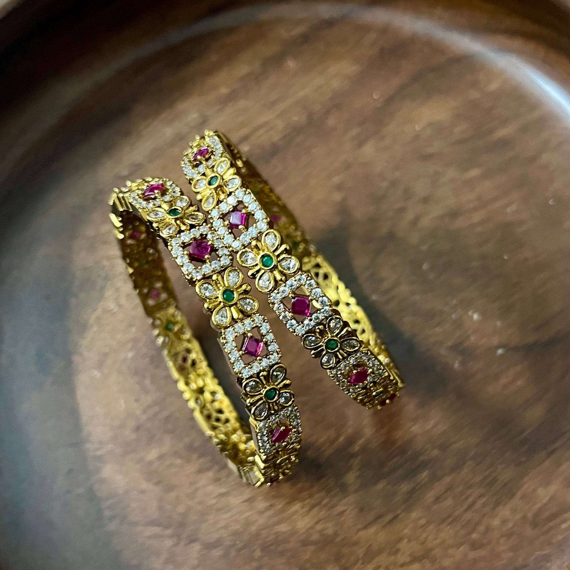 floral bangles, gold tone bangles, ruby stone bangles, emerald bangles, traditional bangles, Indian bangles, designer bangles, festive jewelry, wedding bangles, bridal bangles, ethnic jewelry, imitation bangles, kundan style bangles, party wear bangles, temple jewelry, handmade bangles, statement bangles, pushpa valli bangles, Indian accessories, South Indian jewelry