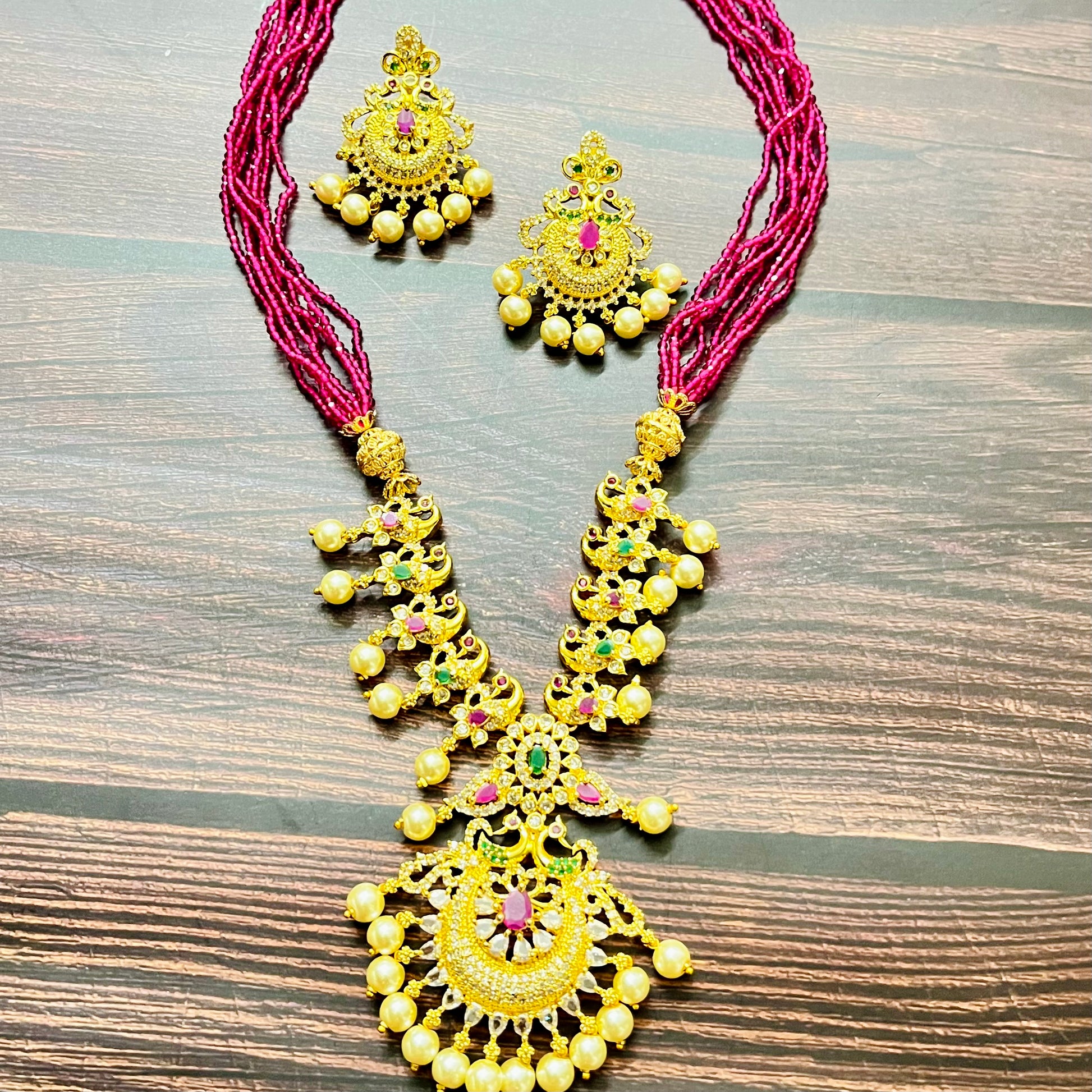 traditional jewelry, temple jewelry, bridal necklace, pearl necklace, ethnic wear, gold plated jewelry, South Indian jewelry, handcrafted jewelry, festive wear, statement necklace, antique finish, Indian bride, designer jewelry, heavy necklace set, wedding collection, navratna stones, ruby emerald combo, temple earrings, kundan work, goddess jewelry, mangalsutra look, cultural heritage, pink thread necklace, handmade jewelry, fashion accessories