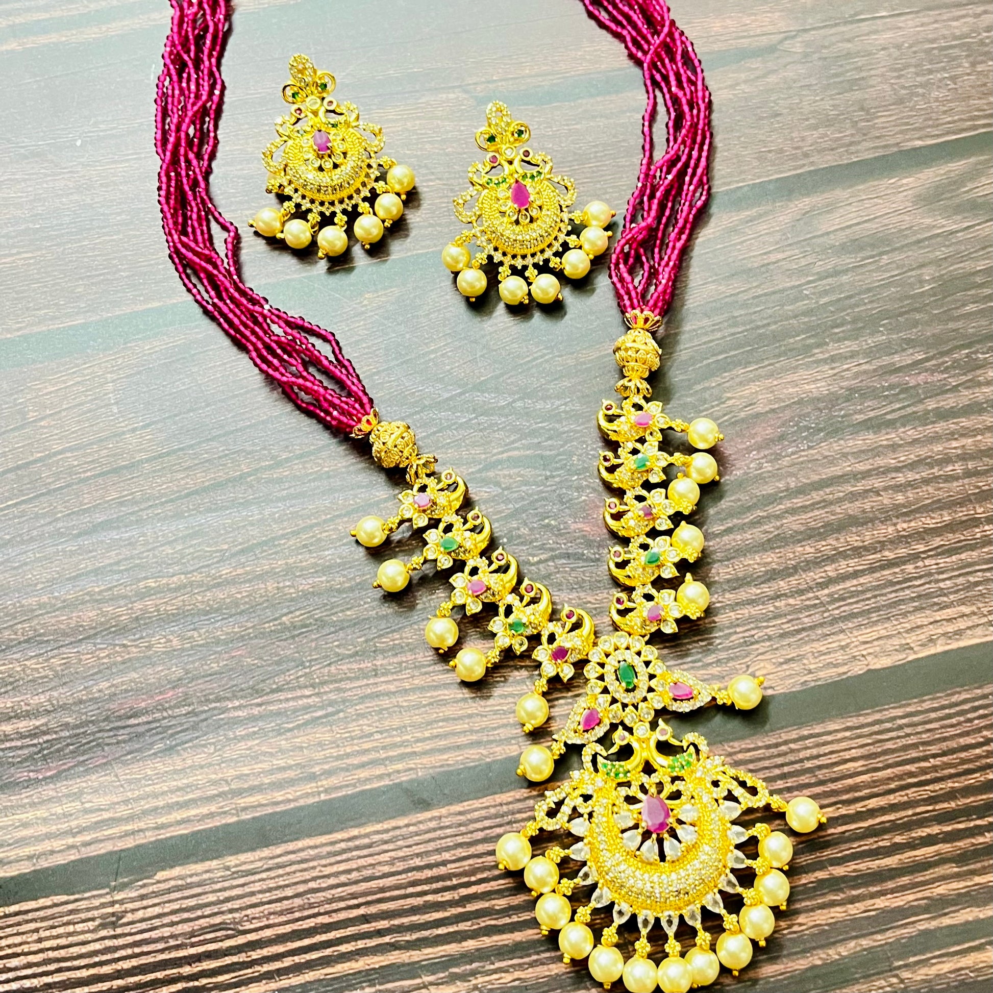 traditional jewelry, temple jewelry, bridal necklace, pearl necklace, ethnic wear, gold plated jewelry, South Indian jewelry, handcrafted jewelry, festive wear, statement necklace, antique finish, Indian bride, designer jewelry, heavy necklace set, wedding collection, navratna stones, ruby emerald combo, temple earrings, kundan work, goddess jewelry, mangalsutra look, cultural heritage, pink thread necklace, handmade jewelry, fashion accessories