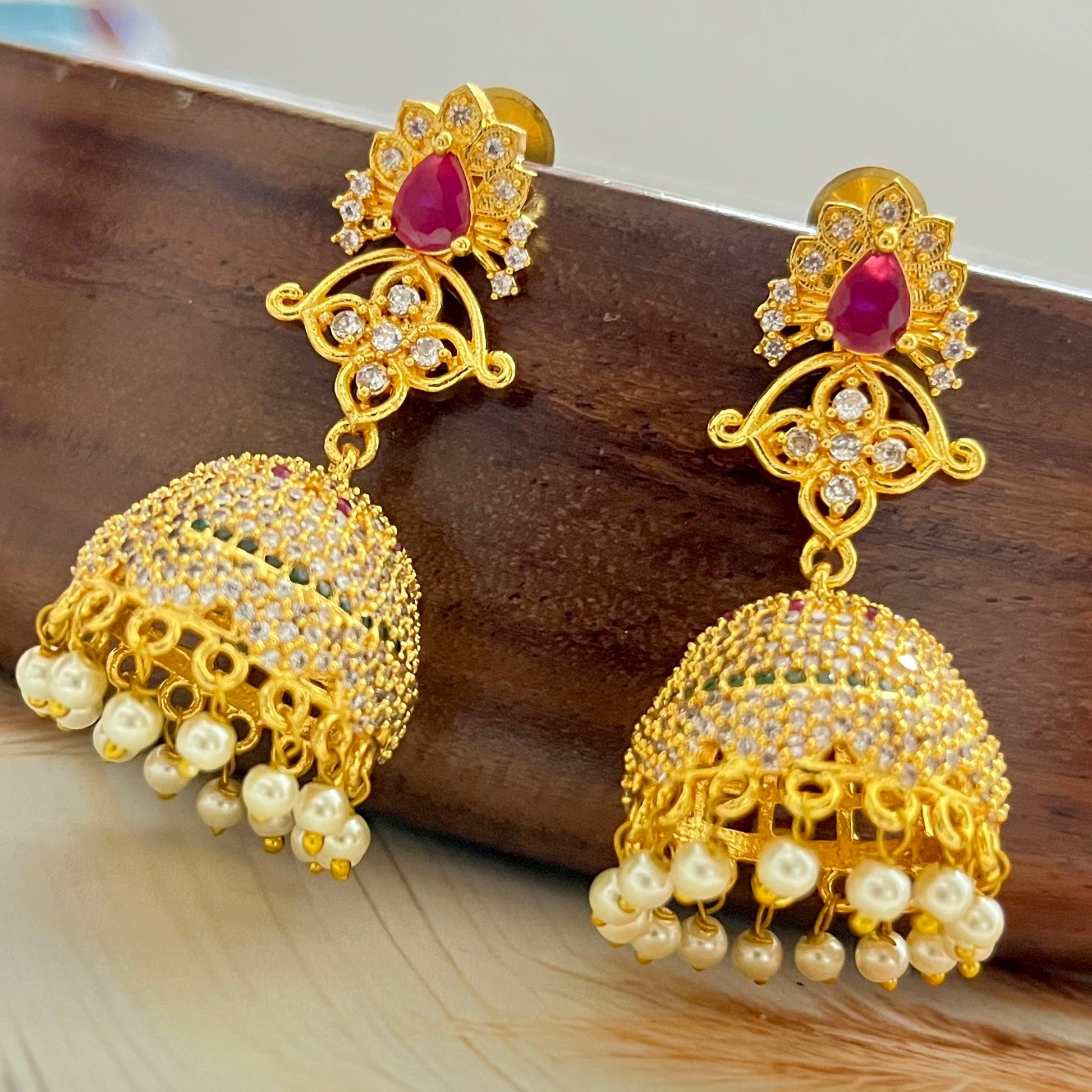 ruby stone jhumka earrings, gold jhumka earrings, traditional jhumka earrings, bridal jhumka earrings, ethnic gold earrings, Indian jhumka earrings, gold plated jhumkas, wedding jewelry for women, temple jewelry earrings, red stone jhumka, pearl drop jhumka, antique gold earrings, festive wear earrings, South Indian jhumka, handcrafted jhumka earrings, CZ stone jhumka, ruby earrings for lehenga, gold earrings for saree, designer jhumka earrings, statement traditional earrings