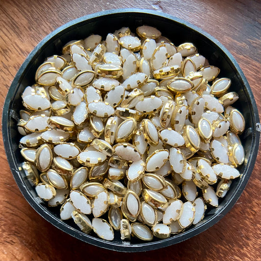 Raw materials for Kundan jewelry making, including uncut stones, gold foil, glass pieces, and other components used in traditional Indian craftsmanship