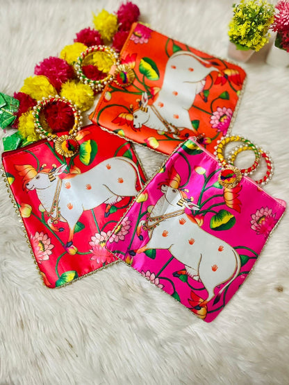 "Pichwai-themed tamboolam bags featuring traditional Indian artwork, adorned with vibrant Pichwai cow and floral motifs, perfect for gifting during festive occasions."