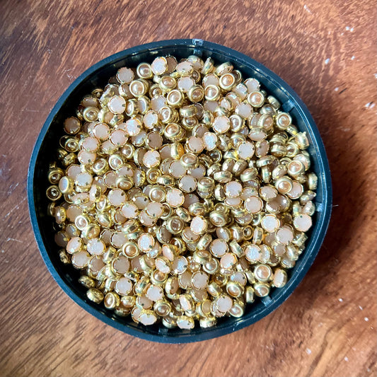 Raw materials for Kundan jewelry making, including uncut stones, gold foil, glass pieces, and other components used in traditional Indian craftsmanship