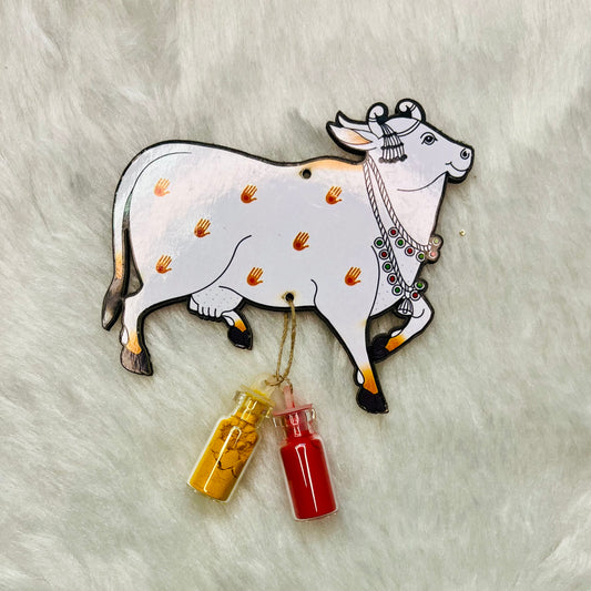 Pichwai-style cow Haldi Kumkum holder with intricate design, featuring a white cow adorned with small handprint motifs, holding small glass bottles of turmeric (haldi) and vermillion (kumkum) for auspicious Indian rituals.

Pichwai cow Haldi Kumkum holder, Indian ritual accessories, traditional Haldi Kumkum decor, handmade Pichwai art, Hindu ceremony essentials