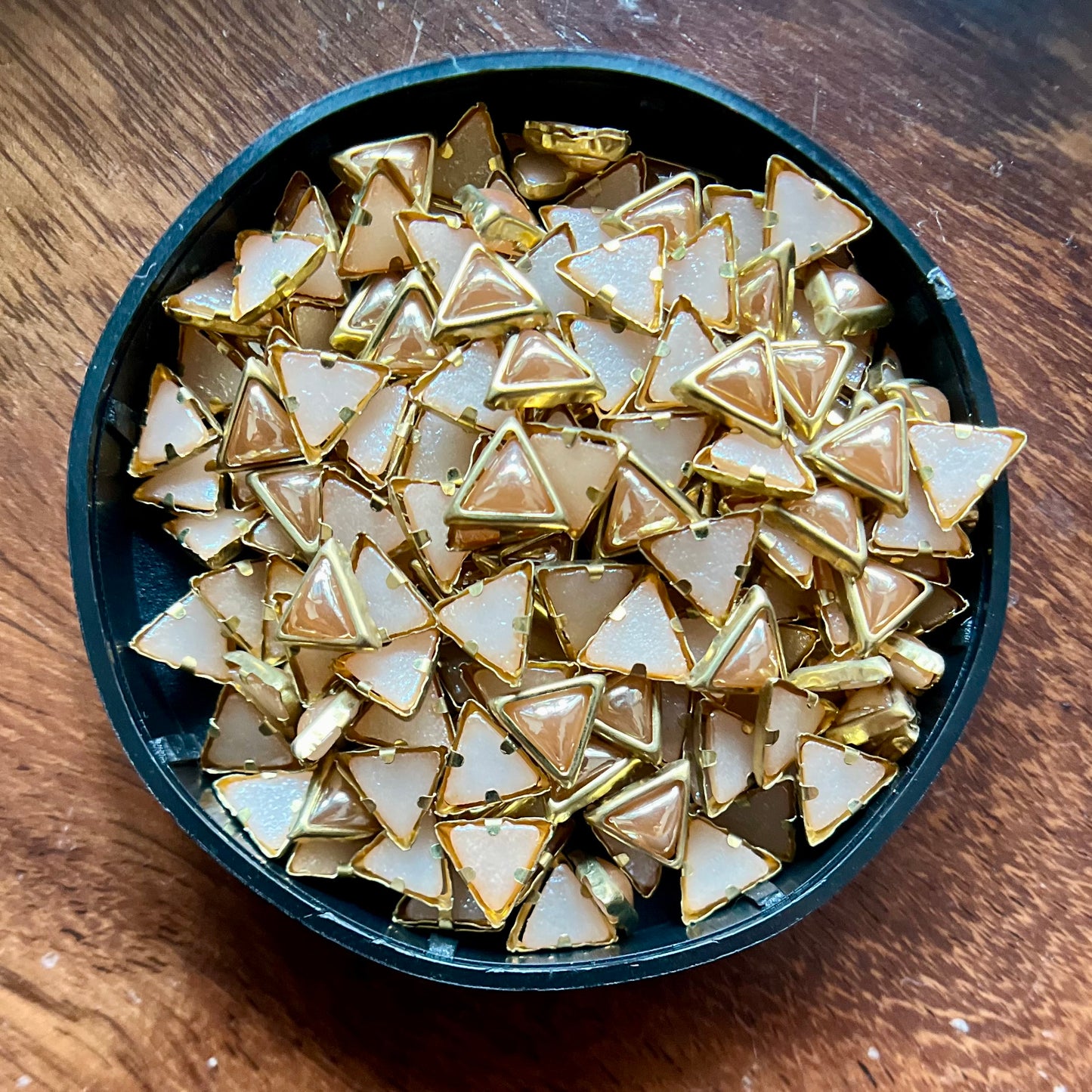 Raw materials for Kundan jewelry making, including uncut stones, gold foil, glass pieces, and other components used in traditional Indian craftsmanship