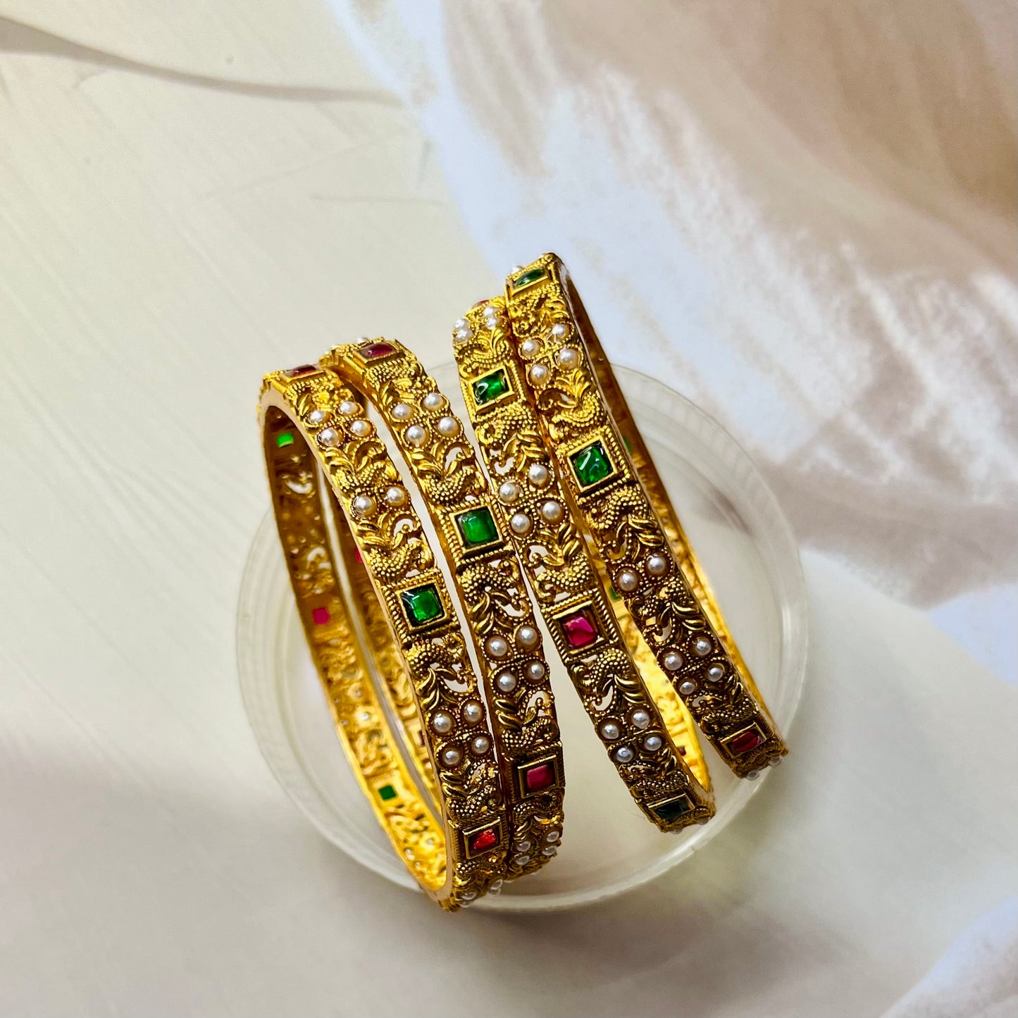 Shop gold look imitation bangles with Pearl, Ruby, and Lakshmi designs. Perfect for weddings, festivals, and everyday wear. Find antique, temple, and bridal styles in affordable, gold-polish bangles. Our Indian, handmade bangles add elegance to any ethnic look. Discover traditional bangles with goddess-inspired, divine details and a real-gold finish.